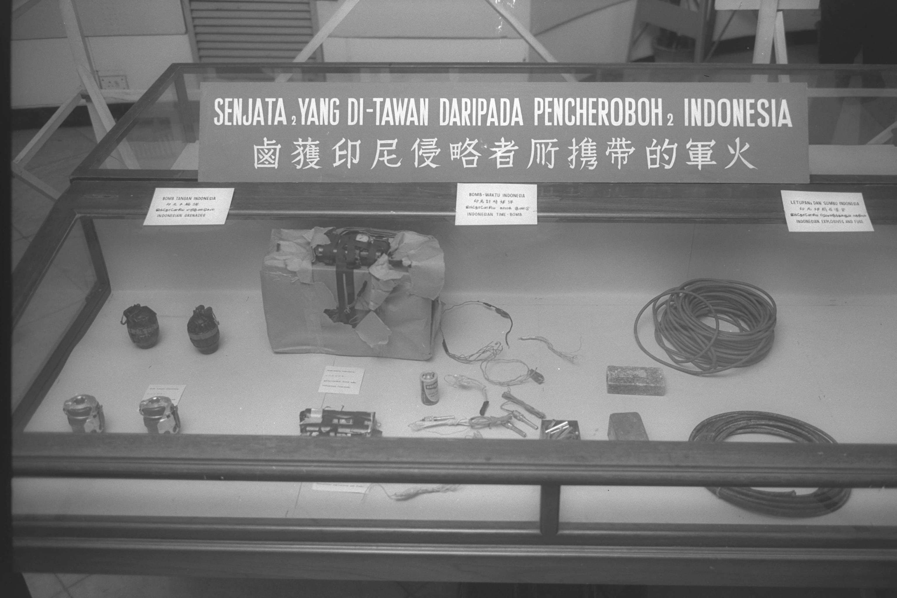 Weapons of Indonesian intruders displayed in a glass case, including grenades, a time bomb, and explosive materials.